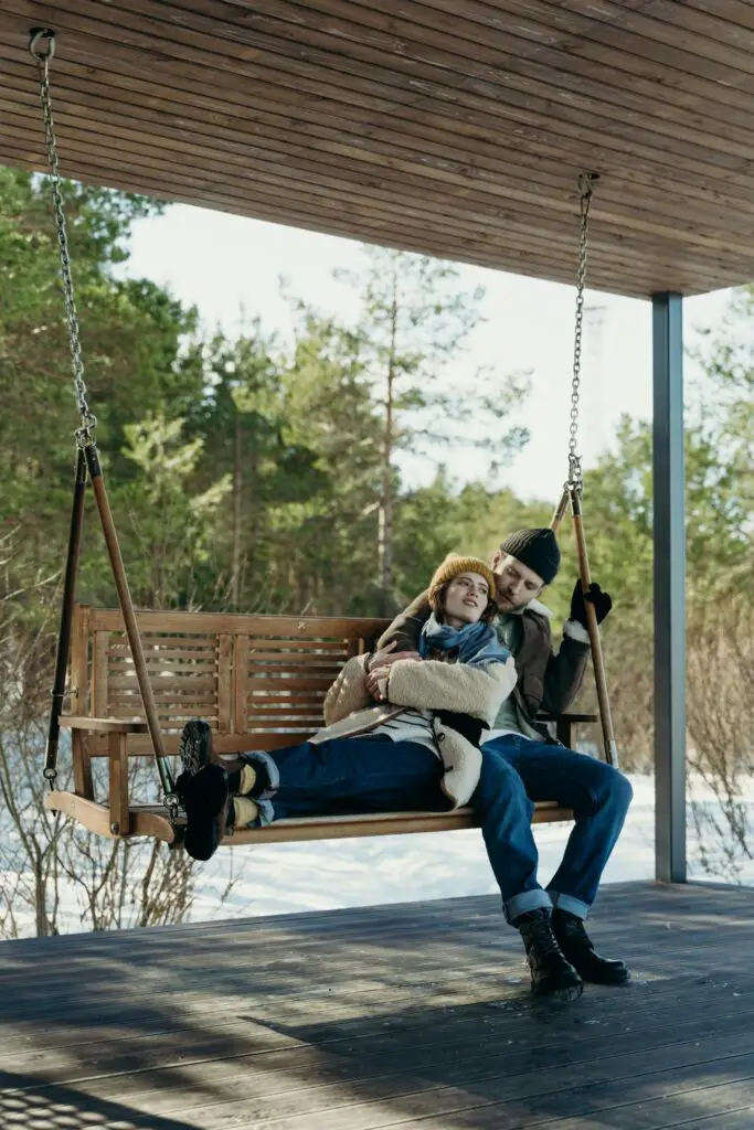 A Romantic Couple Sitting on a Wooden Swing while Embracing